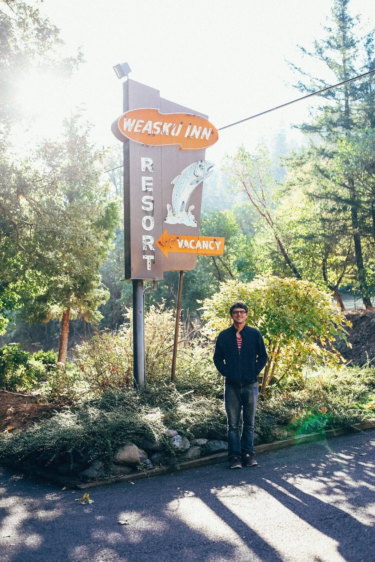 Man standing near a resort sign.