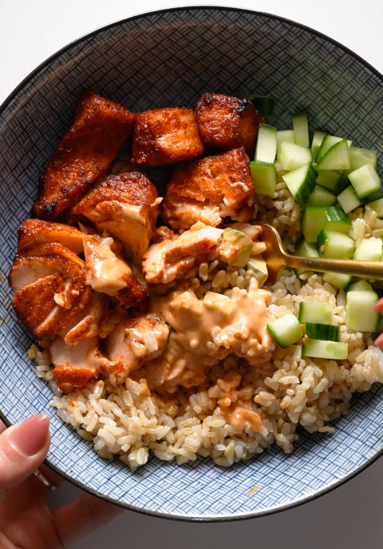 Rice, salmon, and cucumber in a bowl.