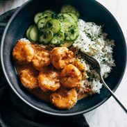 A bowl of shrimp and greens with some rice.