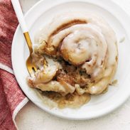 Cinnamon roll on a plate with a fork.