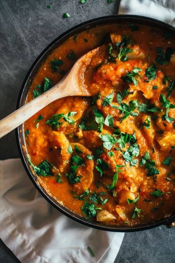 Spanish Chicken and Potatoes in a black skillet with a wooden spoon.